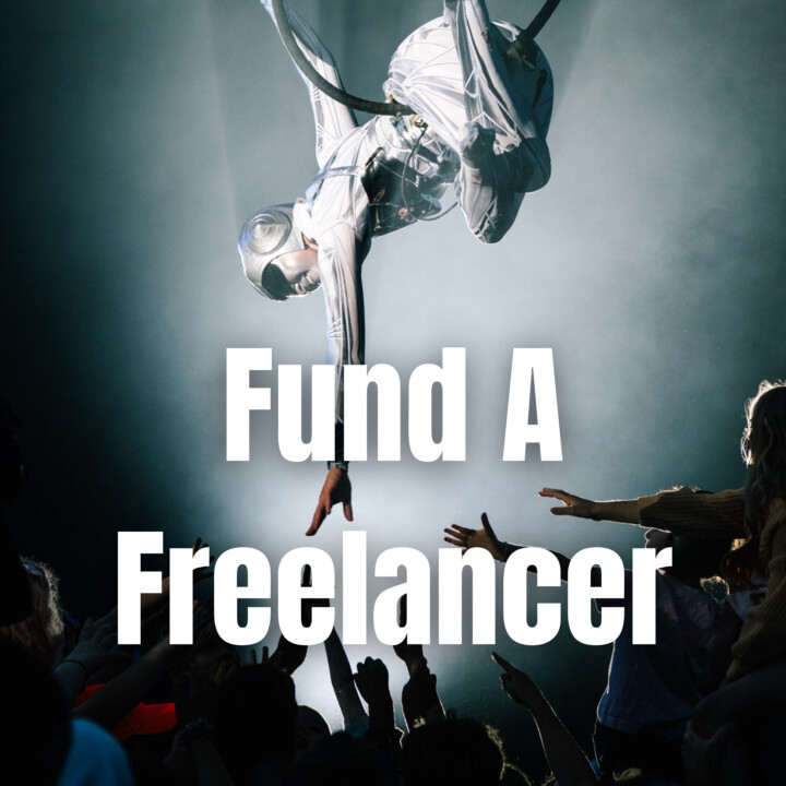A shining alien performer suspends from a hoop, their extended arm meets a shadowed crowd of hands reaching up to touch them. Text reads 'Fund A Freelancer'